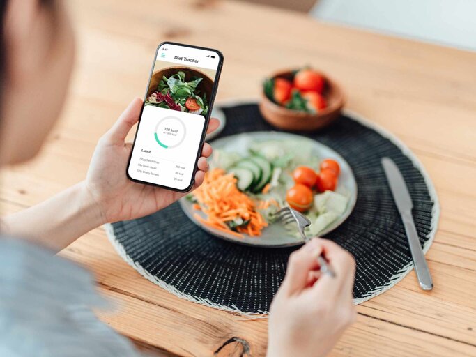 Junge Frau trackt ihre Mahlzeit mit dem Handy | © Getty Images/Oscar Wong