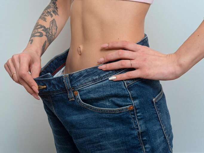 Frau hält zu weite Hose von ihrem Bauch | © Getty Images/Francesco Carta fotografo