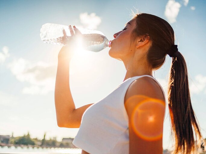 Frau trinkt aus Wasserflasche in Sonnenschein | © Getty Images/RICOWde