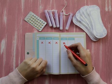 Person streicht Tage in Menstruationskalender ab | © Getty Images/Isabel Pavia