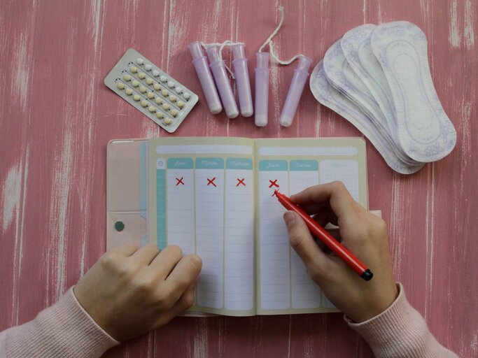 Person streicht Tage in Menstruationskalender ab | © Getty Images/Isabel Pavia