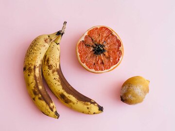 Verschimmelte Banane, Blutorange und Zitrone auf pinkem Hintergrund | © Getty Images/Tanja Ivanova