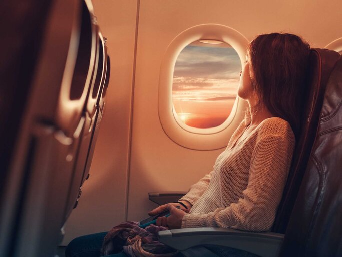 Frau sitzt im Flugzeug und schaut aus dem Fenster | © Getty Images/martin-dm