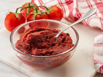 Glasschale mit Tomatenmark steht auf einer Marmorplatte. | © Getty Images / BURCU ATALAY TANKUT