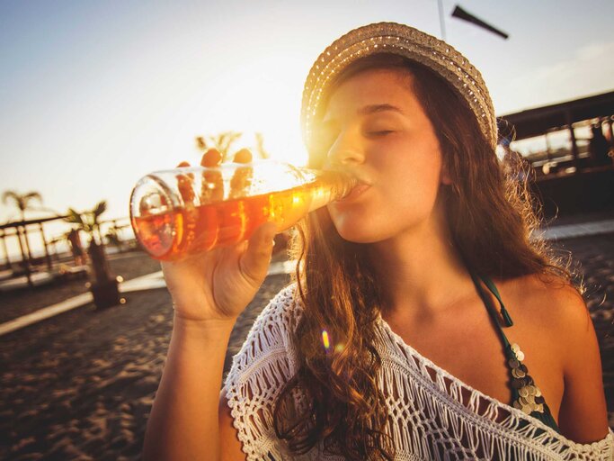 Frau trinkt Bier am Strand | © Getty Images/mihailomilovanovic