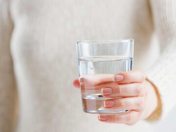 Eine Frau hält ein Glas Wasser in den Händen | © Getty Images/Mikhail Blavatskiy