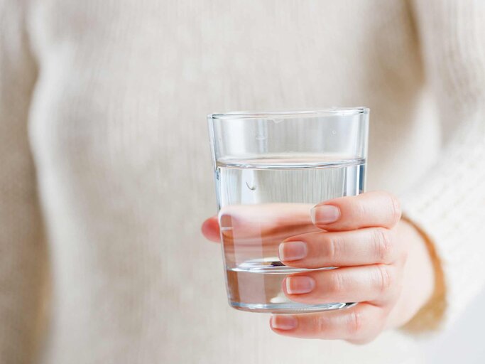 Eine Frau hält ein Glas Wasser in den Händen | © Getty Images/Mikhail Blavatskiy