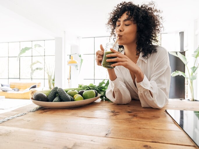 Eine junge Frau trinkt einen grünen Smoothie | © GettyImages/Daniel de la Hoz