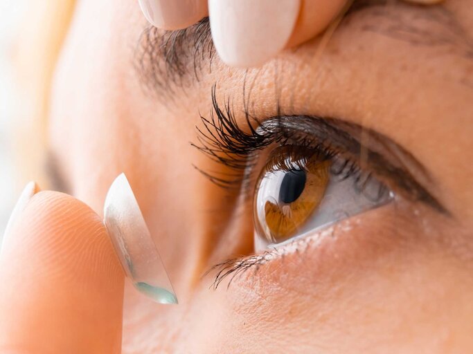 Nahaufnahme einer Frau mit braunen Augen, die sich Kontaktlinsen in die Augen legt | © Getty Images/Volodymyr Kalyniuk