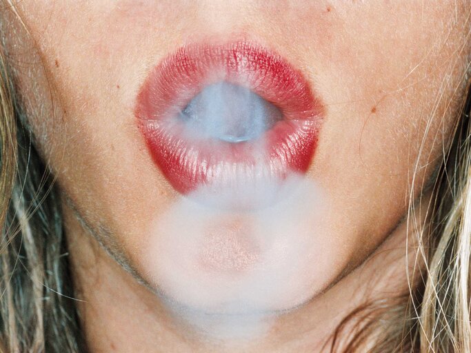 Rote Lippen formen mit Rauch einen Kringel | © Getty Images/Holger Scheibe