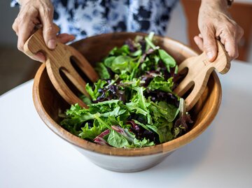 Frau mischt Salat in einer Schüssel | © Getty Images/OsakaWayne Studios