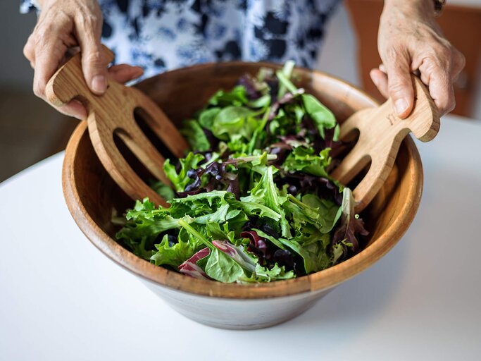 Frau mischt Salat in einer Schüssel | © Getty Images/OsakaWayne Studios