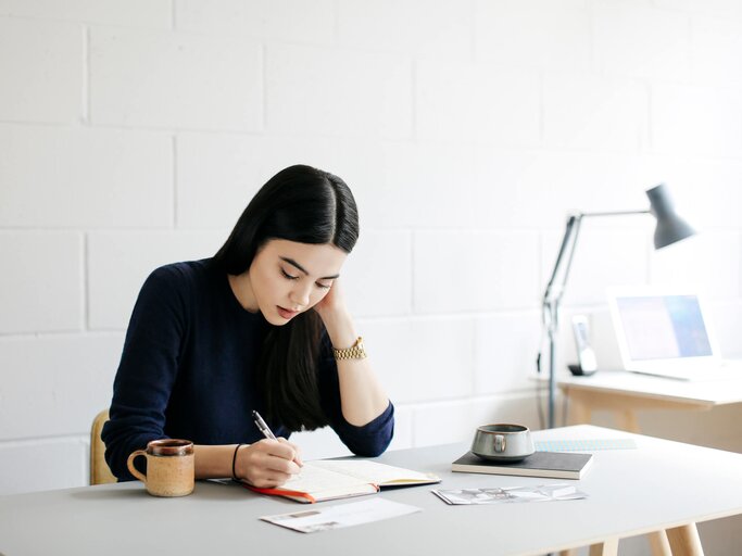 Frau sitzt im Büro am Schreibtisch | © Getty Images/Alys Tomlinson