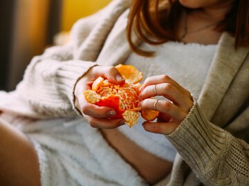 Frau schält Mandarine | © Getty Images/Anna Blazhuk