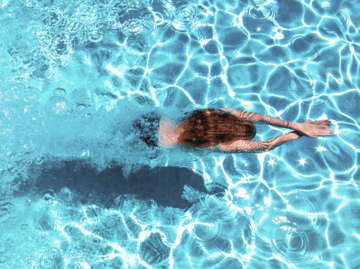 Frau schwimmt in blauem Wasser | © Getty images/Westend61