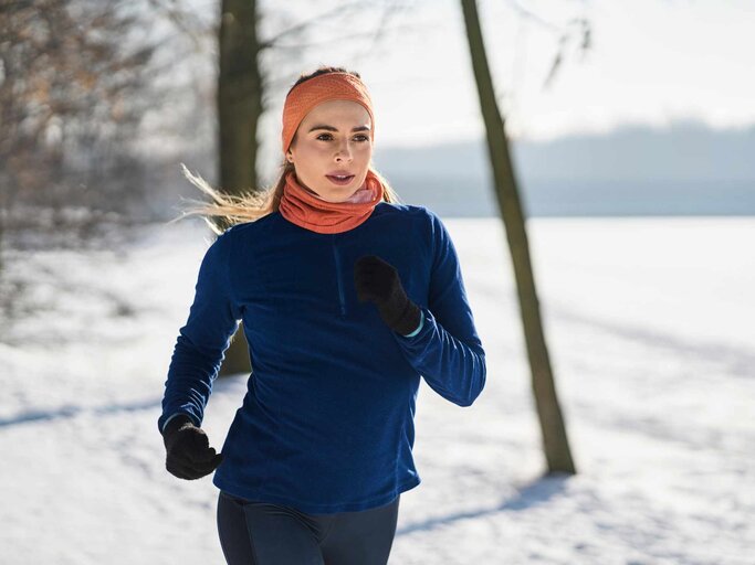 Junge Frau joggt bei Eis und Schnee im Freien | © Getty Images/Westend 61