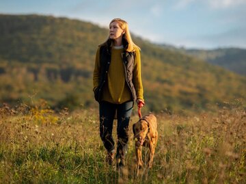 Frau geht Gassi mit Hund in Wiese | © Getty Images/Andrea Obzerova/EyeEm
