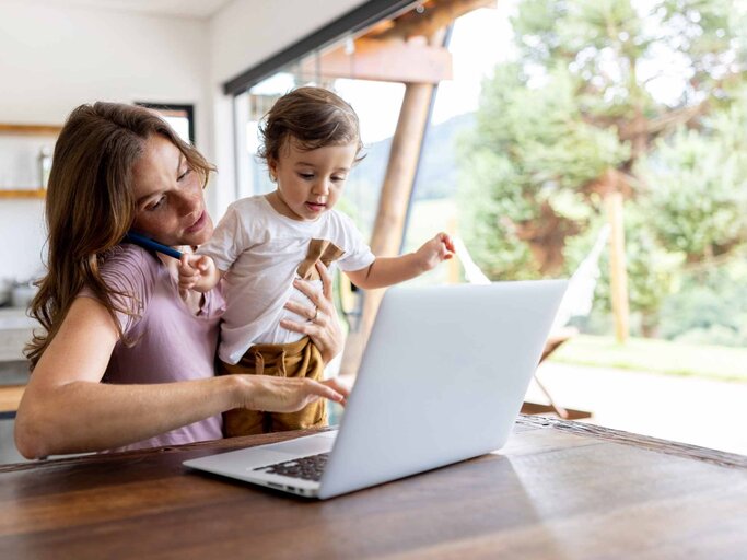 Vielbeschäftigte Mutter, die zu Hause arbeitet, während sie sich um ihren Sohn kümmert | © Getty Images/andresr