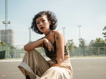 Frau mit Tattoos kniet aus Asphalt | © staticnak1983