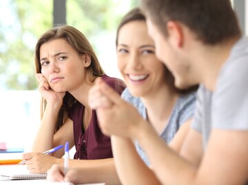 Frau schaut eifersüchtig während ihr Freund mit einer anderen Frau spricht | © Getty Images/AntonioGuillem