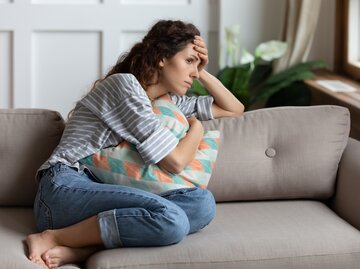 Frau sitzt nachdenklich auf der Couch | © Getty Images/fizkes