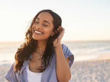 Frau lächelt am Strand | © Getty Images/Ridofranz