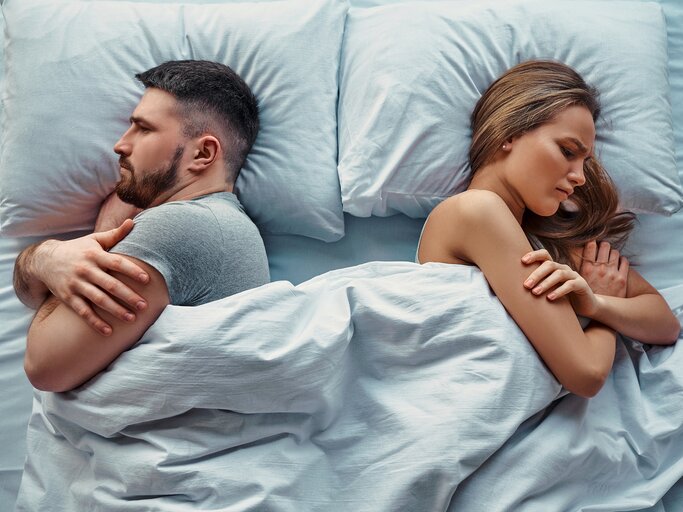 Paar liegt abgewandt voneinander im Bett | © Getty Images/Harbucks