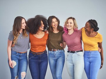 Gruppe von jungen Frauen steht lächelnd zusammen | © Getty Images/LaylaBird