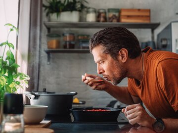 Ein Mann ist in der Küche und probiert die Soße | © GettyImages/miniseries