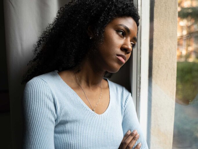Frau lehnt Kopf an Fenster und schaut deprimiert | © Getty Images/Paolo Cordoni