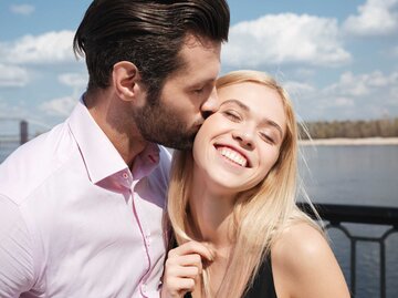 Mann küsst Partnerin auf die Wange | © Getty Images/DeanDrobot