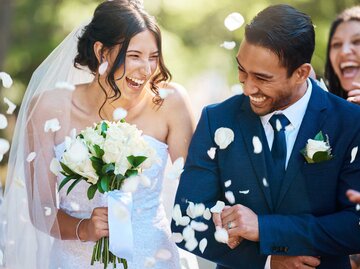 Frisch vermähltes Brautpaar wird mit Rosenblüten beworfen | © Getty Images/PeopleImages