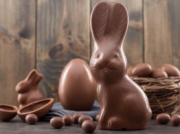 Schokoladen-Osterhase, Eier und Süßigkeiten auf rustikalem Hintergrund | © Getty Images/AND-ONE