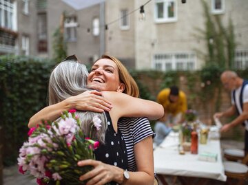 Mutter und Tochter umarmen sich im Garten | © Getty Images/Halfpoint Images