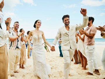 Hochzeitspaar wird am Strand von Freunden bejubelt | © Getty Images/Thomas Barwick