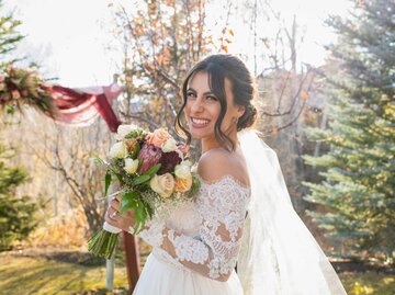 Braut hält Brautstrauß in der Hand und lächelt | © Getty Images/Tony Anderson
