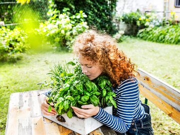 Eine junge Frau umarmt ihre gepflanzten Kräuter | © GettyImages/Westend61