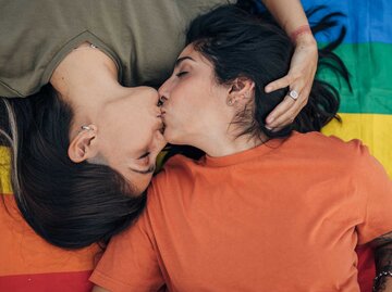 Zwei Frauen küssen sich vor einer Regenbogenflagge | © Getty Images/South_agency