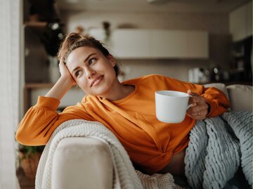 Junge Frau entspannt mit einer Tasse Tee auf der Couch | © Getty Images/Halfpoint Images