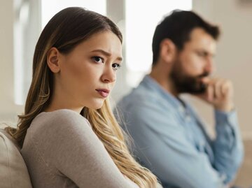 Besorgte junge Frau sitzt zu Hause auf dem Sofa und ignoriert ihren Freund, der neben ihr sitzt | © Getty Images/Goran13