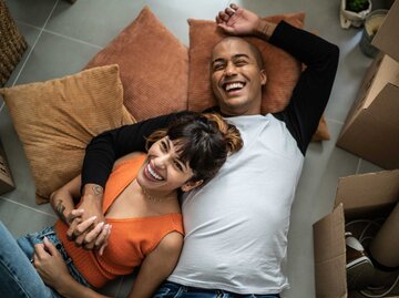 Glückliches junges Paar, das in einem neuen Zuhause auf dem Boden liegt  | © Getty Images/FG Trade
