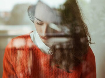 Nachdenkliche Frau hinter einer Fensterscheibe | © Getty Images/Westend61