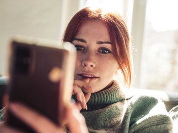 Rothaarige Frau schaut auf ihr Handy | © Getty Images/Guido Mieth