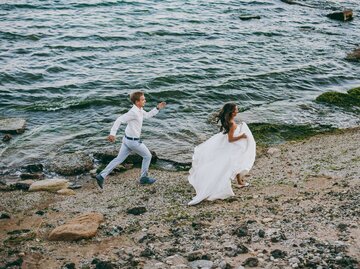 Brautpaar läuft am Strand herum | © Getty Images/ViDi Studio