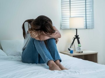 Frau sitzt mit Liebeskummer auf dem Bett | © Getty Images/Kiwis