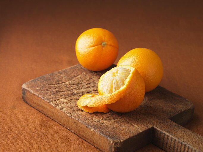 Orangen und Orangenschalen auf Holzbrett | © Getty Images/Diana Miller
