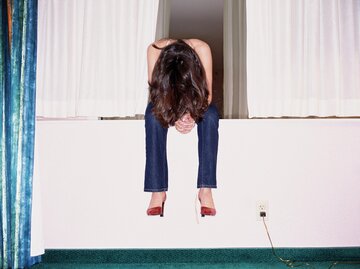 Frau sitzt und lässt den Kopf hängen | © Getty Images/Gravity Images
