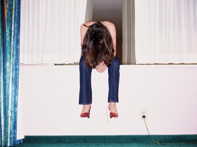 Frau sitzt und lässt den Kopf hängen | © Getty Images/Gravity Images