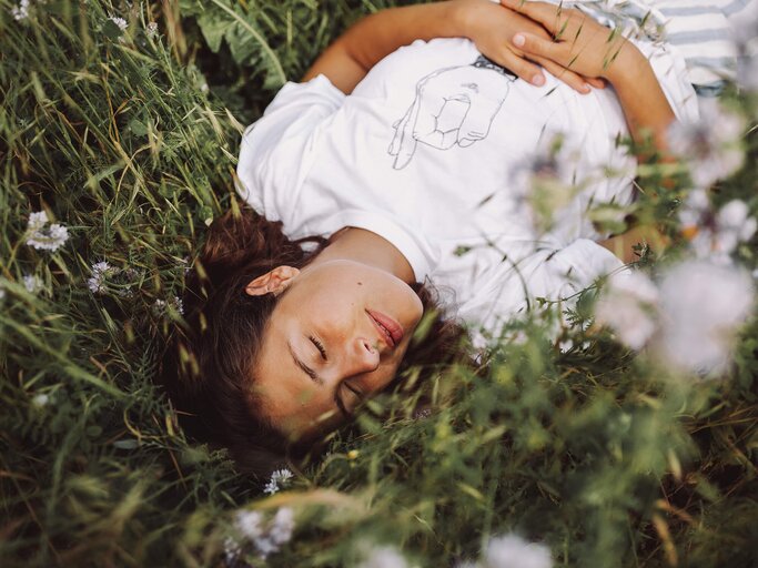 Frau liegt glücklich im Gras | © Getty Images/Cathleen Zornow / EyeEm