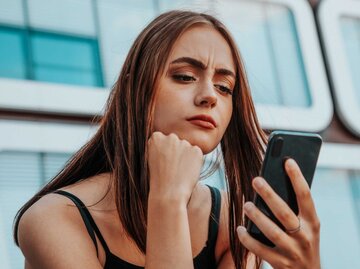 Junge Frau schaut verwundert auf ihr Smartphone | © Getty Images/Finn Hafemann
